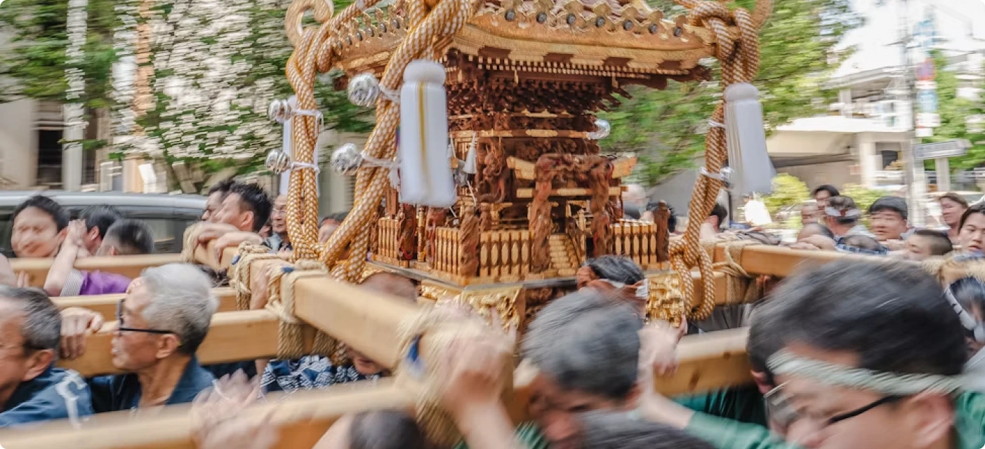 People in yukata dancing under paper lanterns at a summer festival.